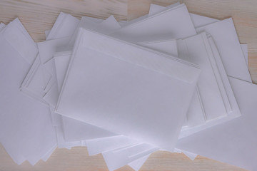 outgoing correspondence: a lot of blank white envelopes on a wooden desk in the office, low contrast