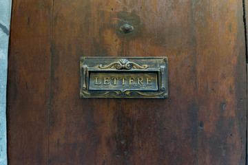 Old fashioned brass postbox on a wooden door