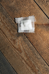 Bandage gauze with tape lying on wooden floor. Top view.