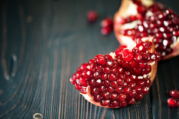 Ripe pomegranate fruit on a old black wooden vintage background. Background with copy space. Horizontal.