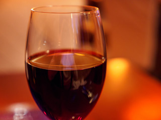 Closeup macro detail of a glass of red wine in a warmly lit restaurant. Strasbourg, France. Travel and fine dining.