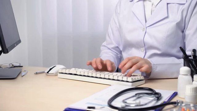Physician typing a report, checking patient's x-ray, keeping medical records. Healthcare and medicine