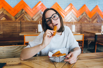 Woman eats fried cheese sticks in a cafe