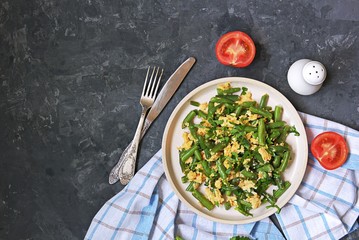 Light dinner or lunch, fried green asparagus beans with scramble egg on a white clay plate. Georgian cuisine