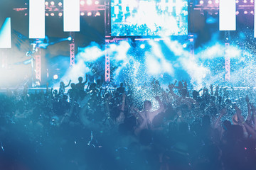 silhouettes of concert crowd in front of bright stage lights, pool party