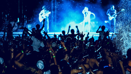 silhouettes of concert crowd in front of bright stage lights, pool party