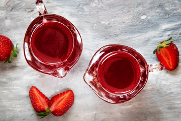 Delicious strawberry jelly in a glass and ripe strawberries on a gray background