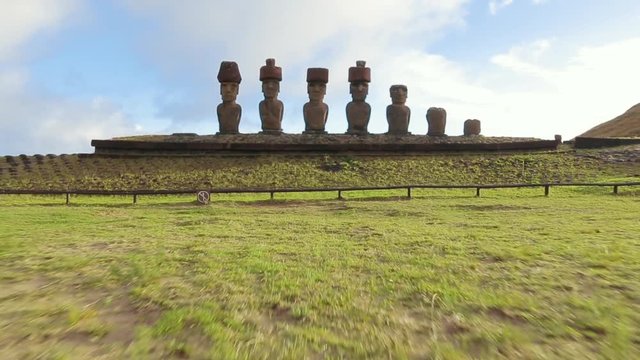 Zoom-out shot of the Moai stone head statues. Heads with hat-like additions facing inland of the island. Easter Island, Chile.