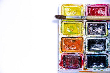 Palette with watercolors and brushes for paints on a white background. Watercolor paints. Brushes. Top and front view