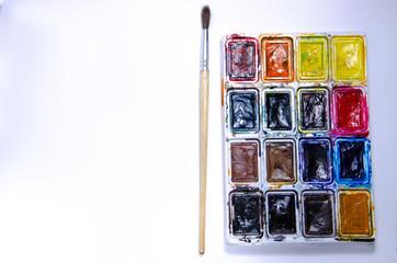 Palette with watercolors and brushes for paints on a white background. Watercolor paints. Brushes. Top and front view