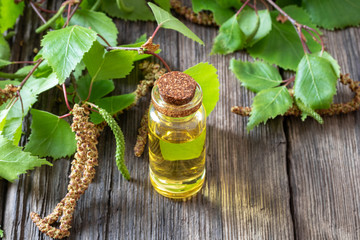 A bottle of birch essential oil with birch branches