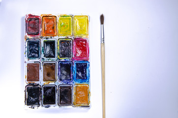 Palette with watercolors and brushes for paints on a white background. Watercolor paints. Brushes. Top and front view