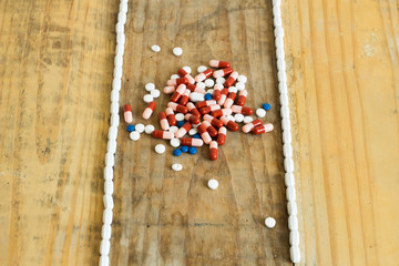 Drugs of various colors in the form of capsules, tablets and gelatin on dirty wooden background