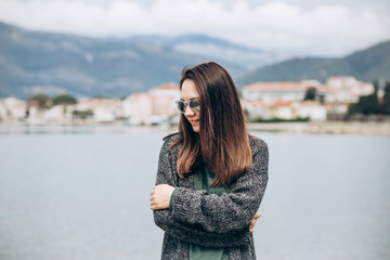 Portrait of a beautiful young fashionable girl on the background of the sea and the coastal city.