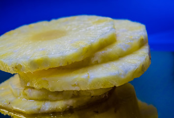 Slices of the fresh and cut pineapple on blue and bright background. Tropical, citrus fruit. A natural product for health. Exotic.