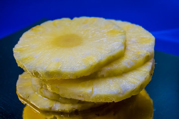 Slices of the fresh and cut pineapple on blue and bright background. Tropical, citrus fruit. A natural product for health. Exotic.