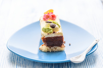 Cake with cream photographed close-up on a blue plate on a wooden background.