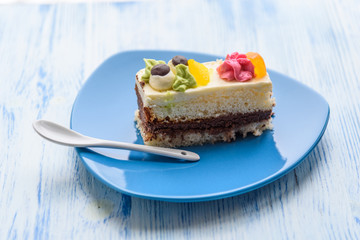 Cake with cream photographed close-up on a blue plate on a wooden background.
