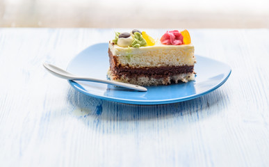 Cake with cream photographed close-up on a blue plate on a wooden background.
