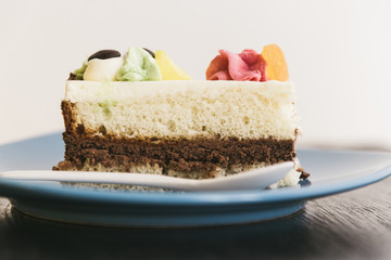 Cake with cream photographed close-up on a blue plate on a wooden background.