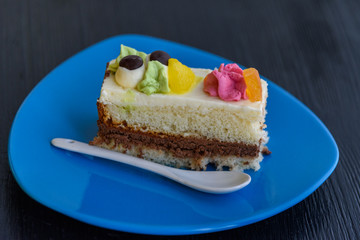 Cake with cream photographed close-up on a blue plate on a wooden background.