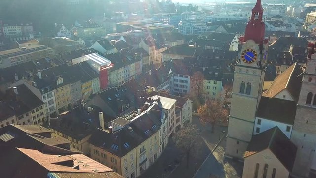 Drone flight with aerial view above church in old town of Winterthur in Switzerland. Tower and building roofs from above. Dynamic, stabilized and smooth shots of European town.