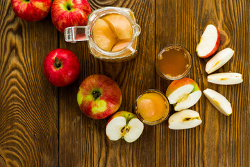 red apples and fresh juice in a jug on the kitchen table, top view