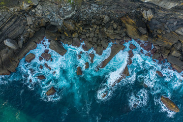 Detail of sea waves colors breaking in the coast of Lekeitio, Basque country - drone aerial view