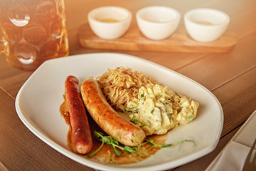 sausages with potatoes and sauerkraut with a beer on the table overlooking the lake
