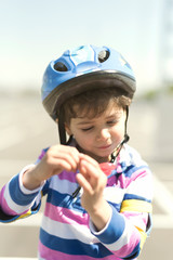 Fototapeta na wymiar Little kid adjusting bike helmet in sunny day