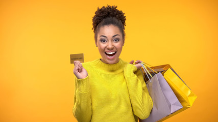 Cheerful woman with shopping bags and golden credit card, rich customer service