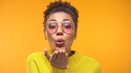 Flirting black woman with healthy smile sending air kiss to camera, close-up