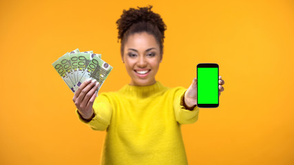 African-American lady showing smartphone and bunch of euros, money transfer