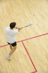 Squash player in action on squash court, back view/Young men playing match of squash