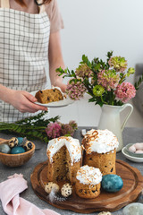 Easter table female serving cake, ranunculus flowers, easter cake, milk bottle, coloured eggs, quail eggs, willow banch, vertical