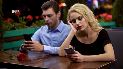Couple spending time scrolling web pages on phones, impact of modern technology