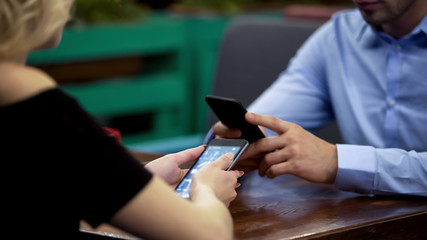 Business family concentrated smartphones on date at restaurant, indifference