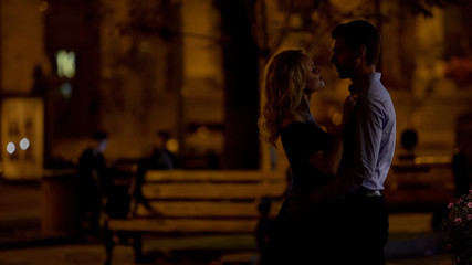 Loving couple hugging and looking at each other on date in night park, romance