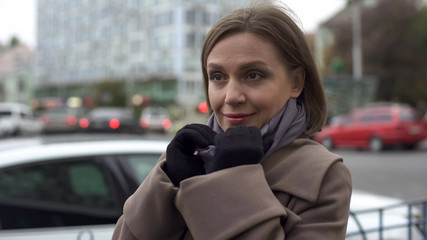 Beautiful woman in her 30s enjoying good day, waiting for taxi on bus stop