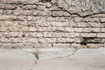 Bad foundation base on old house or building cracked plaster facade wall with brick background