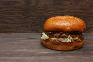 Fresh tasty homemade grilled burger with cheese and salad on wooden background with free space