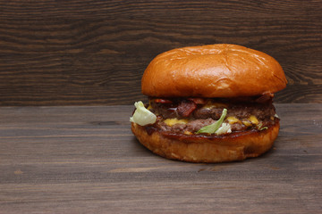 Fresh tasty homemade grilled burger with cheese and salad on wooden background with free space