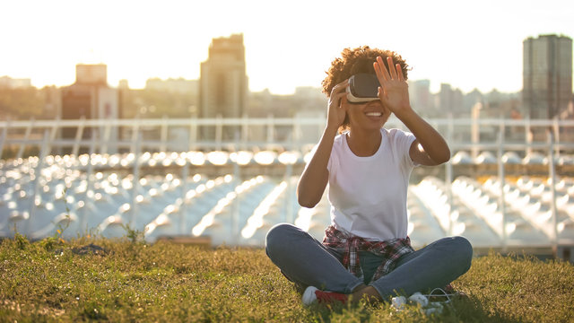 Curly haired lady using virtual reality glasses, touching air, modern technology