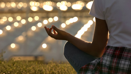 Close-up of slim woman sitting in lotus pose, meditating and practicing yoga