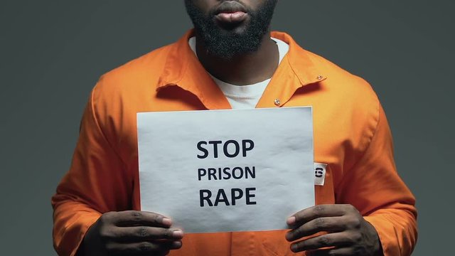 Stop prison rape phrase on cardboard in hands of African-American prisoner