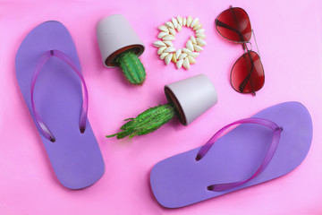 Beach purple flip flops, aviator sunglasses, seashell bracelet and succulent cacti cactus on a pink background. Summer colorful  travel beach flat lay