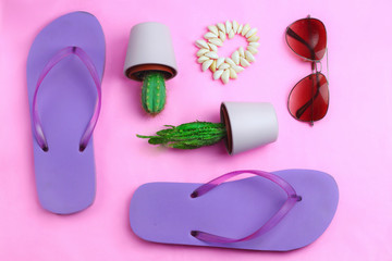 Beach purple flip flops, aviator sunglasses, seashell bracelet and succulent cacti cactus on a pink background. Summer colorful  travel beach flat lay
