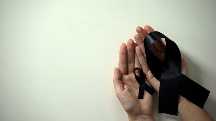 Big and little black ribbons in hands, melanoma awareness, skin cancer treatment