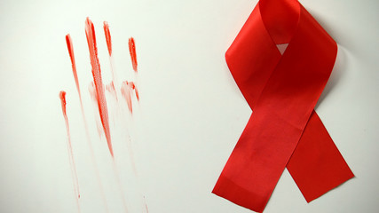 Red ribbon and bloody stains left by male hand on background, AIDS epidemics