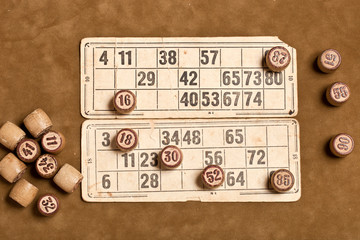 Table game Bingo. Wooden Lotto barrels with bag, playing cards for Lotto game, game for family on brown background